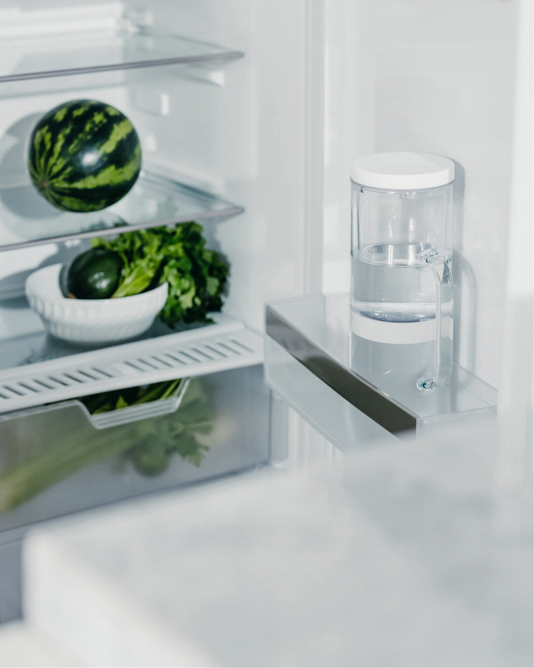 Carafe Filtrante LUCY® beside watermelon in refrigerator.