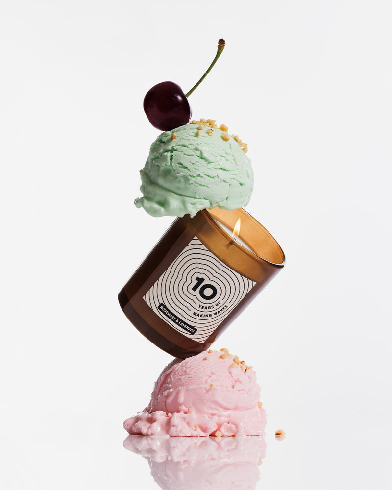 Une bougie marron équilibrée entre deux boules de glace pastel, surmontée d’une cerise.