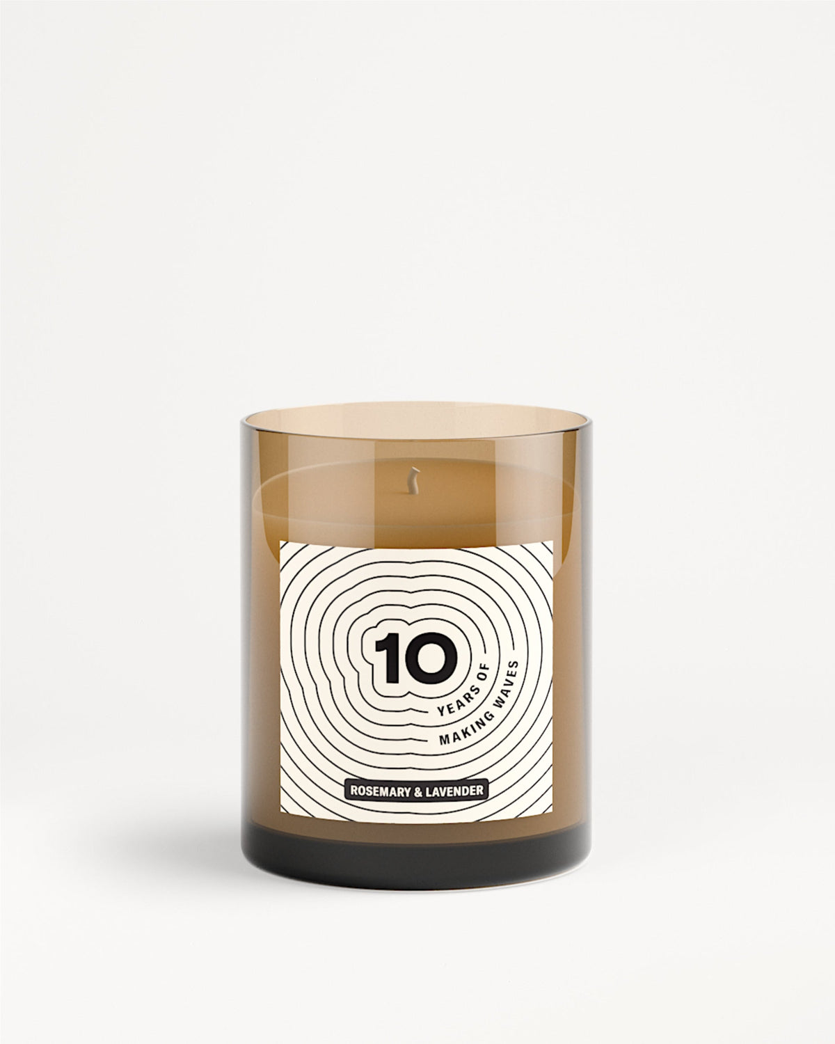 Bougie dans un bocal en verre brun avec étiquette blanche et motif de cercles concentriques.