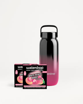 Bouteille réutilisable dégradé noir à rose à côté de deux emballages Waterdrop.