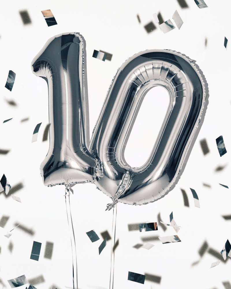 Ballons en feuille d'aluminium argentés formant le chiffre 100 avec des cordons, entourés de confettis.